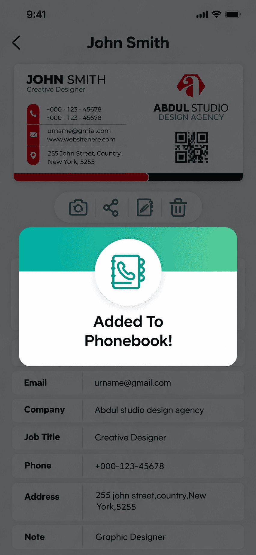 The same card detail dimmed behind an “Added To Phonebook!” confirmation dialog, confirming the contact was written to the device address book